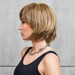 Side view of a woman wearing a blonde bob wig with a fringe.