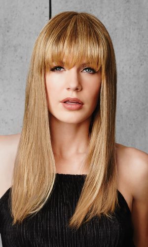 Blonde wig with straight bangs and layered length on a woman.