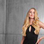 Beautiful blonde hair extension with soft waves on a woman in black dress.