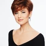 Short, layered auburn wig with side-swept bangs on a woman.