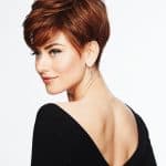 Short red pixie wig styled on a woman with side-swept bangs and layered texture.