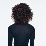 Curly wig with tight ringlets, back view, on a woman in black.