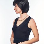 Woman with a short, sleek black bob wig and stylish outfit.