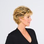 Short swept back wig on a woman with blonde hair and black outfit.