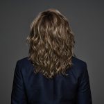 Wavy brown wig styled on a mannequin head with a dark background.