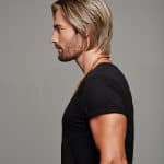 Side profile of a man with blonde wavy wig and black t-shirt.