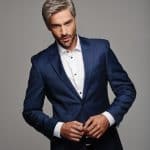Man with gray hair in a navy blue suit and white shirt, looking confident.