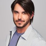 Man with stylish dark brown wig, casual outfit, looking confident.