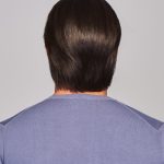 Back view of a short, sleek brown wig on a woman.