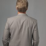 Back view of a woman with short gray wig in a gray blazer.