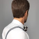 Back view of a man with short brown hair wearing a white shirt and bow tie.