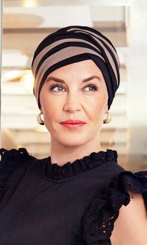 Woman wearing a stylish black and beige striped turban with a black dress.
