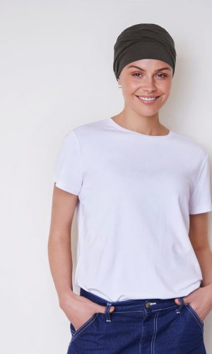 Woman smiling in a white t-shirt and dark headscarf against a plain background.
