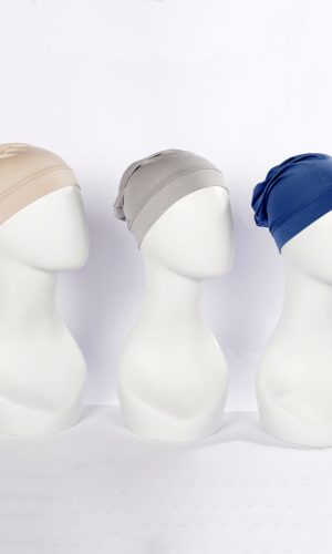 Three sleep caps in beige, grey, and blue on mannequin heads.