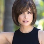 Woman with short brown bob wig with highlights, outdoors.