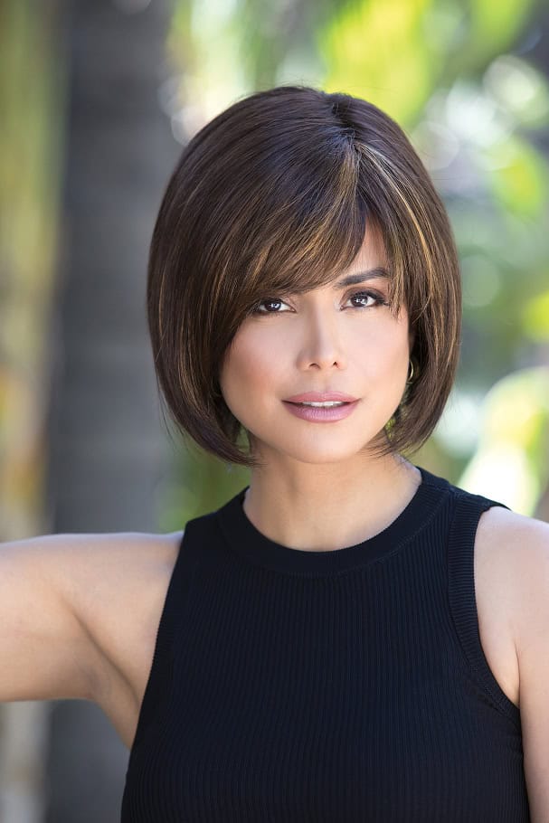 Woman with short brown bob wig with highlights, outdoors.