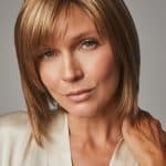 Woman with shoulder-length light brown wig, side-swept bangs, and natural makeup.