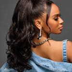 Elegant woman with long, curly hair styled in a ponytail with a claw clip.