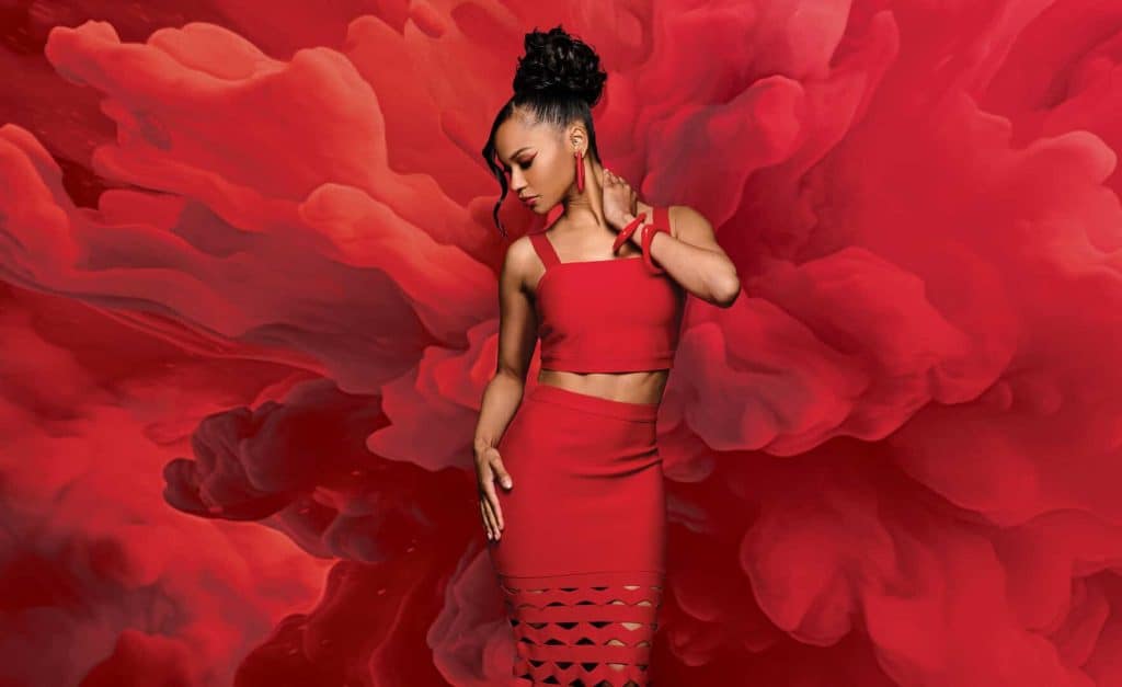 Model wearing a red crop top and skirt with a smoky red background.