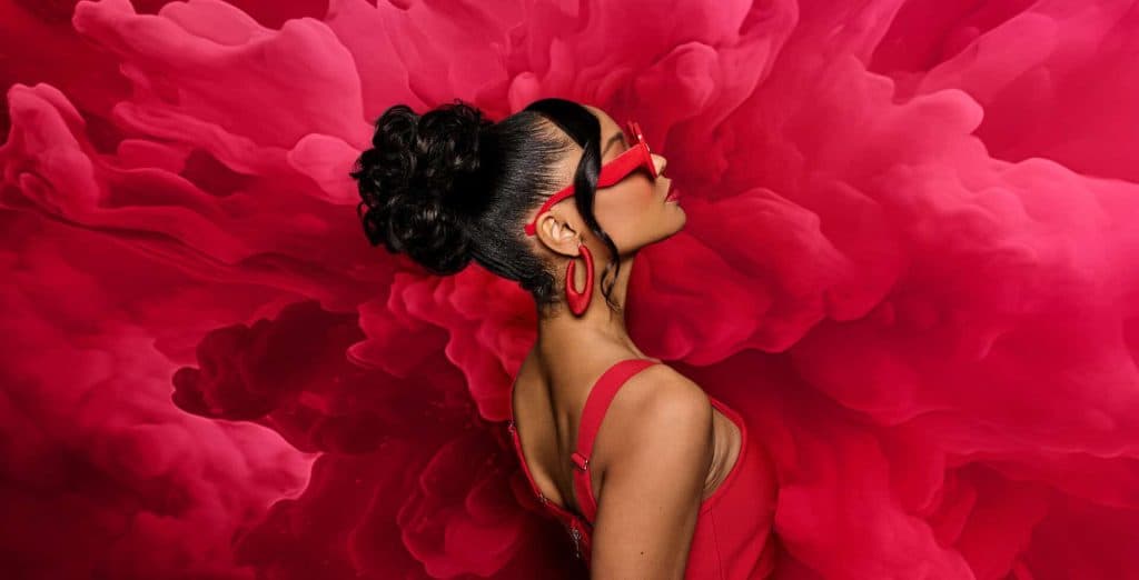 Side profile of a woman with a sleek black updo wig and red accessories.