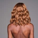 Wavy copper-colored wig on a woman with back facing camera.