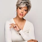 Elegant short gray wig on a mature woman with silver hair and hoop earrings.
