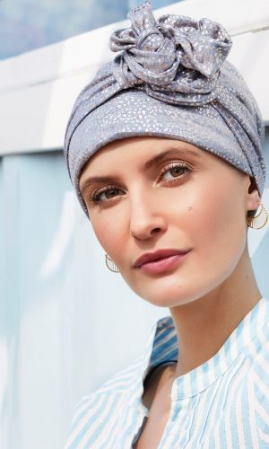 Woman wearing a silver headwrap and striped top outdoors.