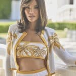 Woman with shoulder-length brown hair wearing a white and gold tropical print outfit.
