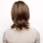 Back view of a woman with medium-length, light brown wig with soft waves.