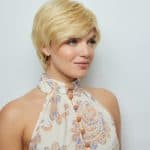 Blonde short wig styled on a woman with a patterned top for Hidden Secrets Wigs.