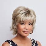 Blonde layered wig with bangs, styled for a natural look.