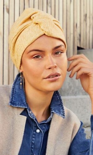 Woman wearing a yellow turban with a denim jacket and beige coat.