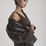 Stylish woman with short gray wig, black leather jacket, and trendy outfit.