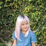 Blonde wig with pastel pink highlights on a young girl outdoors.