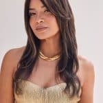 Woman wearing a long, layered brown wig with subtle highlights.