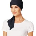 Woman wearing a black short scarf with a white shirt, stylish head covering.
