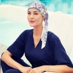 Woman wearing a patterned short scarf by the poolside.