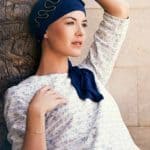 Woman wearing a navy headscarf with decorative silver accents and a matching scarf.