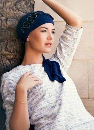 Woman wearing a navy headscarf with decorative silver accents and a matching scarf.