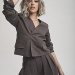 Fashion model with wavy blonde hair in stylish brown suit for wig showcase.