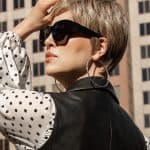 Stylish short wig with layered cut, sunglasses, and hoop earrings in urban setting.