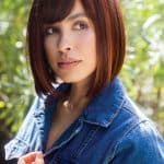 Petite Portia wig in auburn with side-swept bangs on a woman outdoors.