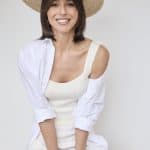 Stylish woman wearing a wide-brim hat and white outfit, showcasing natural hair for wig inspiration.
