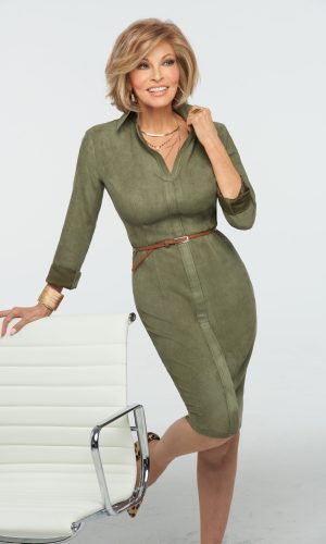 Stylish woman in a green dress with layered necklaces and short blonde hair.