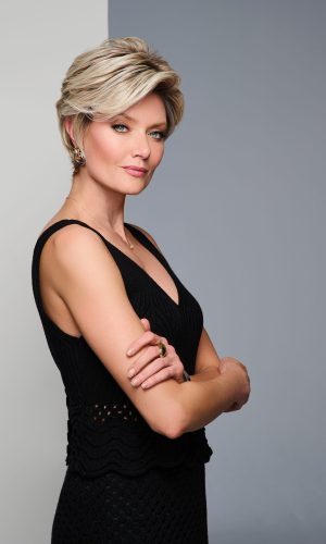 Stylish short blonde wig on a confident woman with crossed arms.