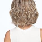 Wavy blonde bob wig with layered curls on a woman from the back.
