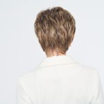 Back view of a short, layered brown wig on a woman in a white blazer.