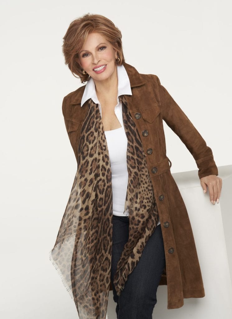 Smiling woman wearing a brown coat and leopard print scarf, posing confidently.