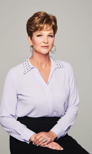 Elegant woman with short hair wearing a white blouse and hoop earrings.
