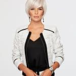Woman with short white wig, stylish black and white outfit, jewelry, and confident pose.